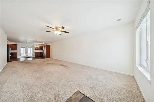 an empty room with a ceiling fan and window