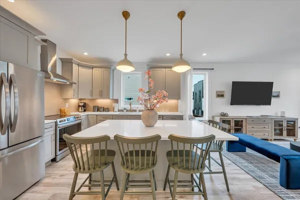 a kitchen with stainless steel appliances kitchen island granite countertop a table chairs sink and cabinets