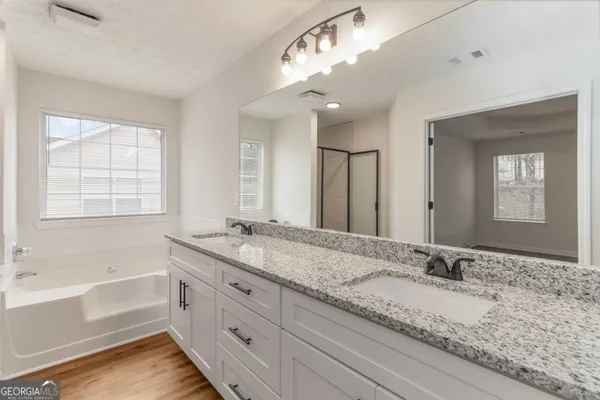 a bathroom with a granite countertop double vanity sink large mirror and a bathtub