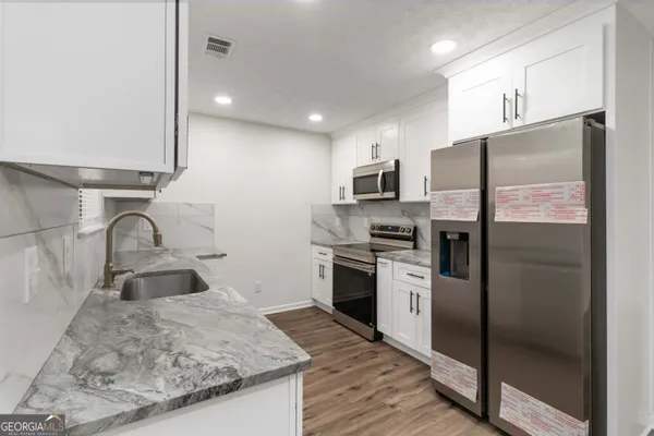 a kitchen with stainless steel appliances granite countertop a refrigerator a stove and a sink