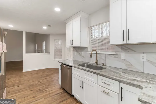 a kitchen with granite countertop a sink and white cabinets