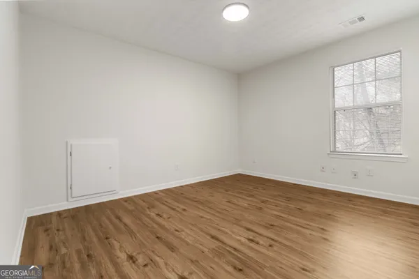 an empty room with wooden floor and windows