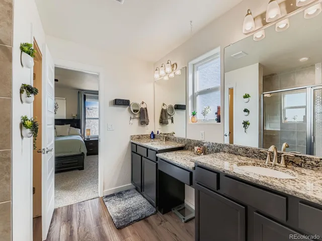 a en suite bathroom with a granite countertop sink a mirror and shower