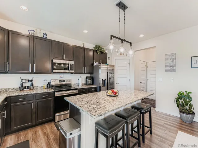 a kitchen with granite countertop kitchen island stainless steel appliances a sink a stove a table and chairs