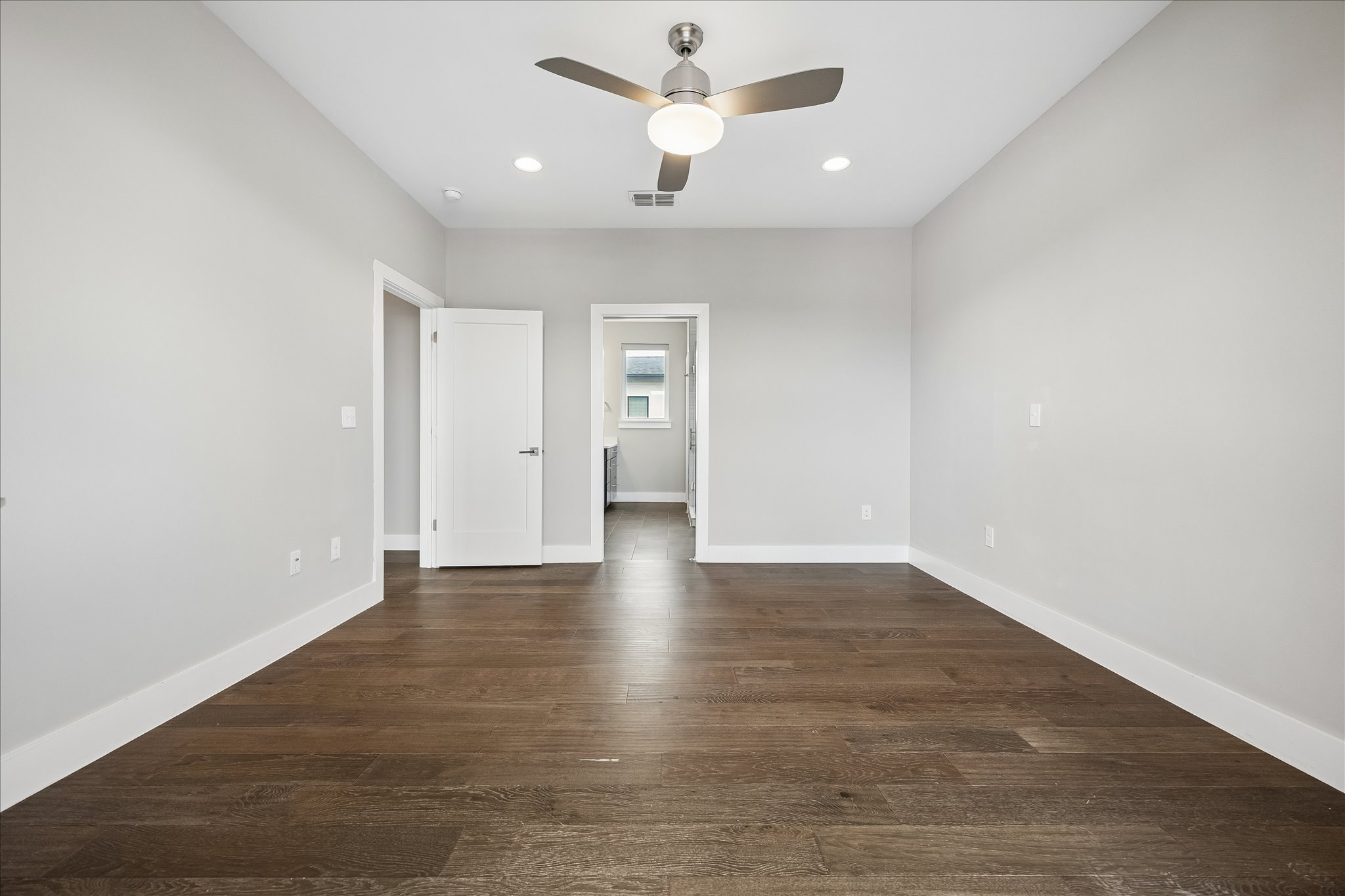 5006 Pecan Springs Road, Unit 6 Austin, TX 78723 - Photo 17 of 30 Rich hardwood floors flow through this well-lit room, featuring a modern ceiling fan and crisp white doors.