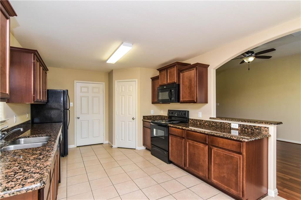 216 Mill Street Anna, TX 75409 - Photo 7 of 22 a kitchen with stainless steel appliances granite countertop a stove a sink and a refrigerator