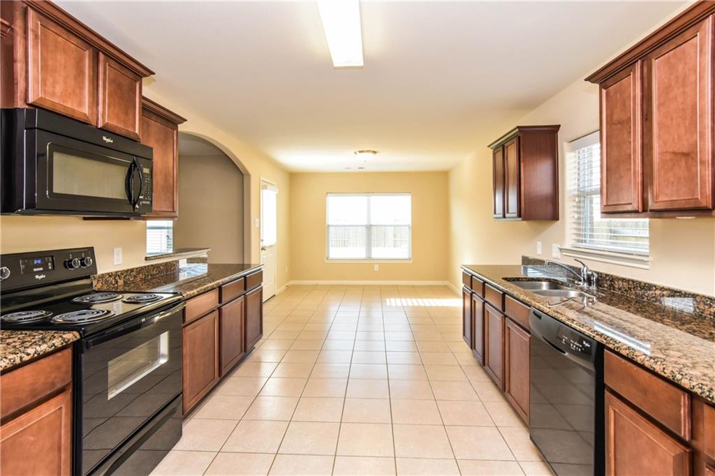 216 Mill Street Anna, TX 75409 - Photo 8 of 22 a kitchen with stainless steel appliances granite countertop a stove top oven a sink dishwasher a dining table and chairs with wooden floor
