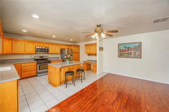 a kitchen with stainless steel appliances granite countertop a refrigerator a sink dishwasher a dining table and chairs with wooden floor