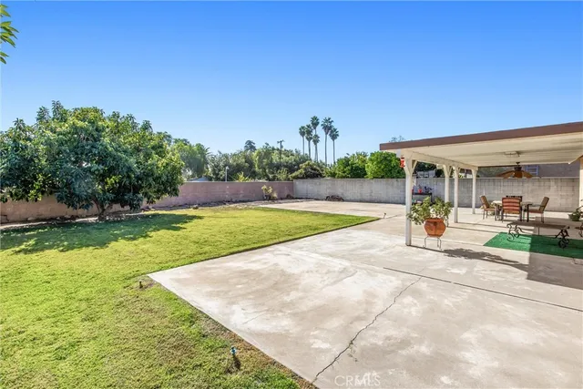 a view of a patio with table and chairs potted plants and floor to ceiling window