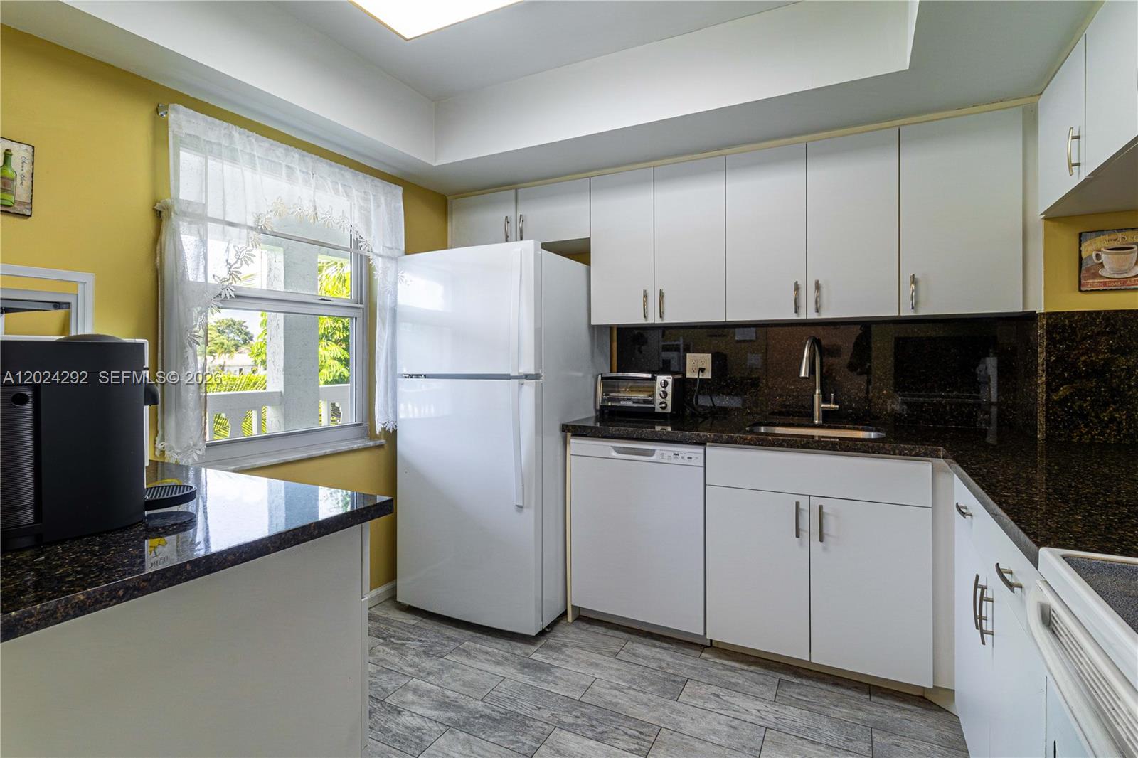9780 Marina Boulevard, Unit 424 Boca Raton, FL 33428 - Photo 8 of 32 a kitchen with a refrigerator a stove a sink a counter top space and cabinets