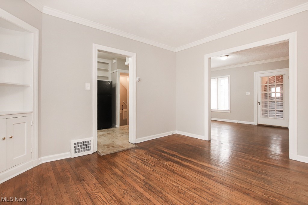 3973 Navahoe Road Cleveland, OH 44121 - Photo 5 of 14 Unfurnished room with visible vents, baseboards, hardwood / wood-style floors, and ornamental molding