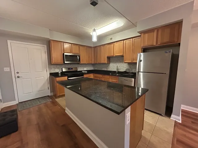 a kitchen with stainless steel appliances granite countertop a refrigerator a sink a stove a microwave and wooden floors