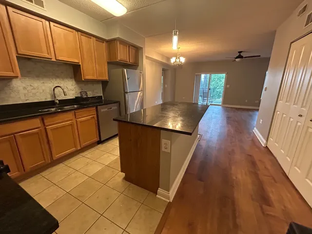 a kitchen with stainless steel appliances granite countertop a refrigerator a sink dishwasher a stove with wooden cabinets and floor