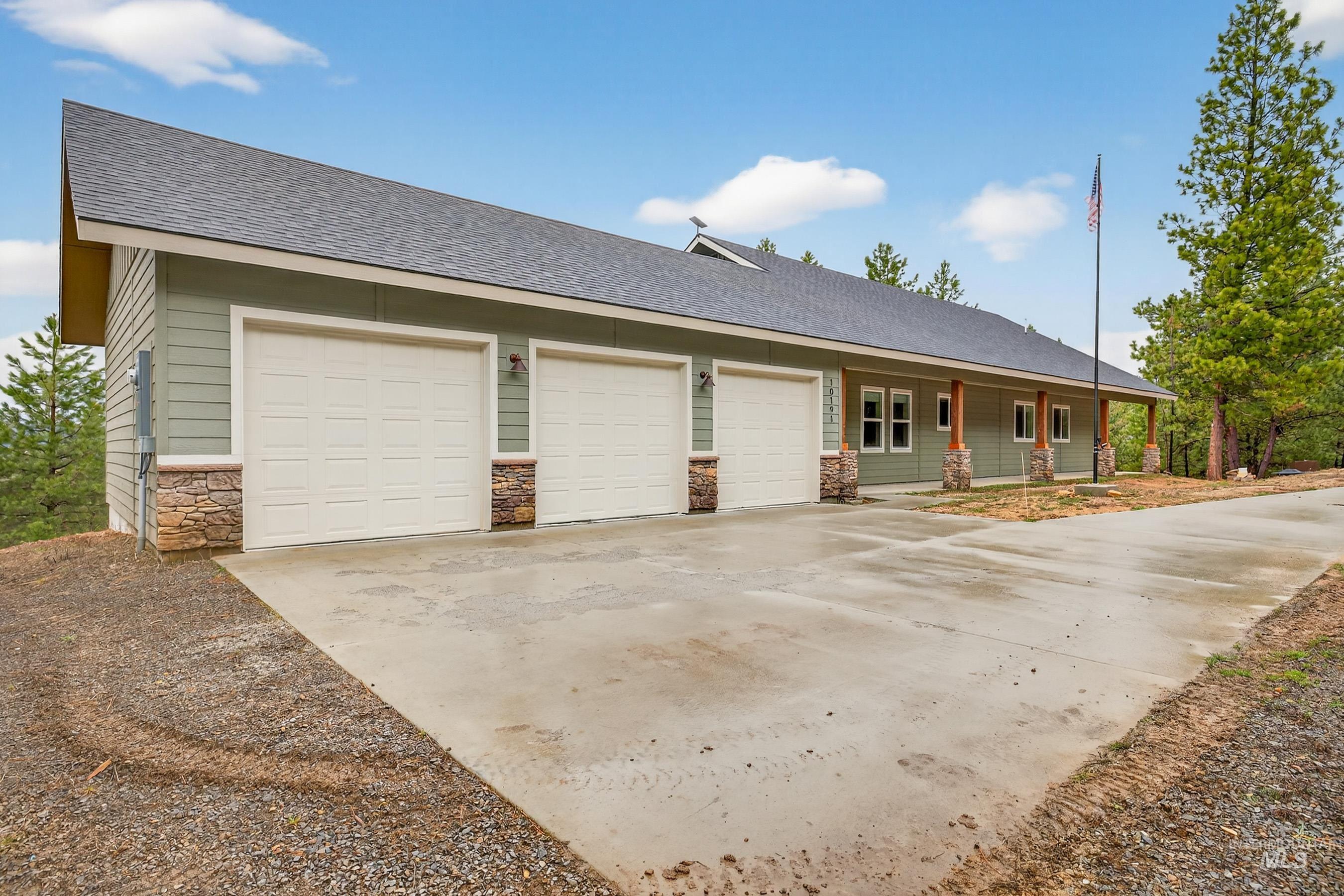 10191 Timberrim Drive Cascade, ID 83611 - Photo 3 of 44 View of front of home with a shingled roof, stone siding, concrete driveway, covered porch, and an attached garage