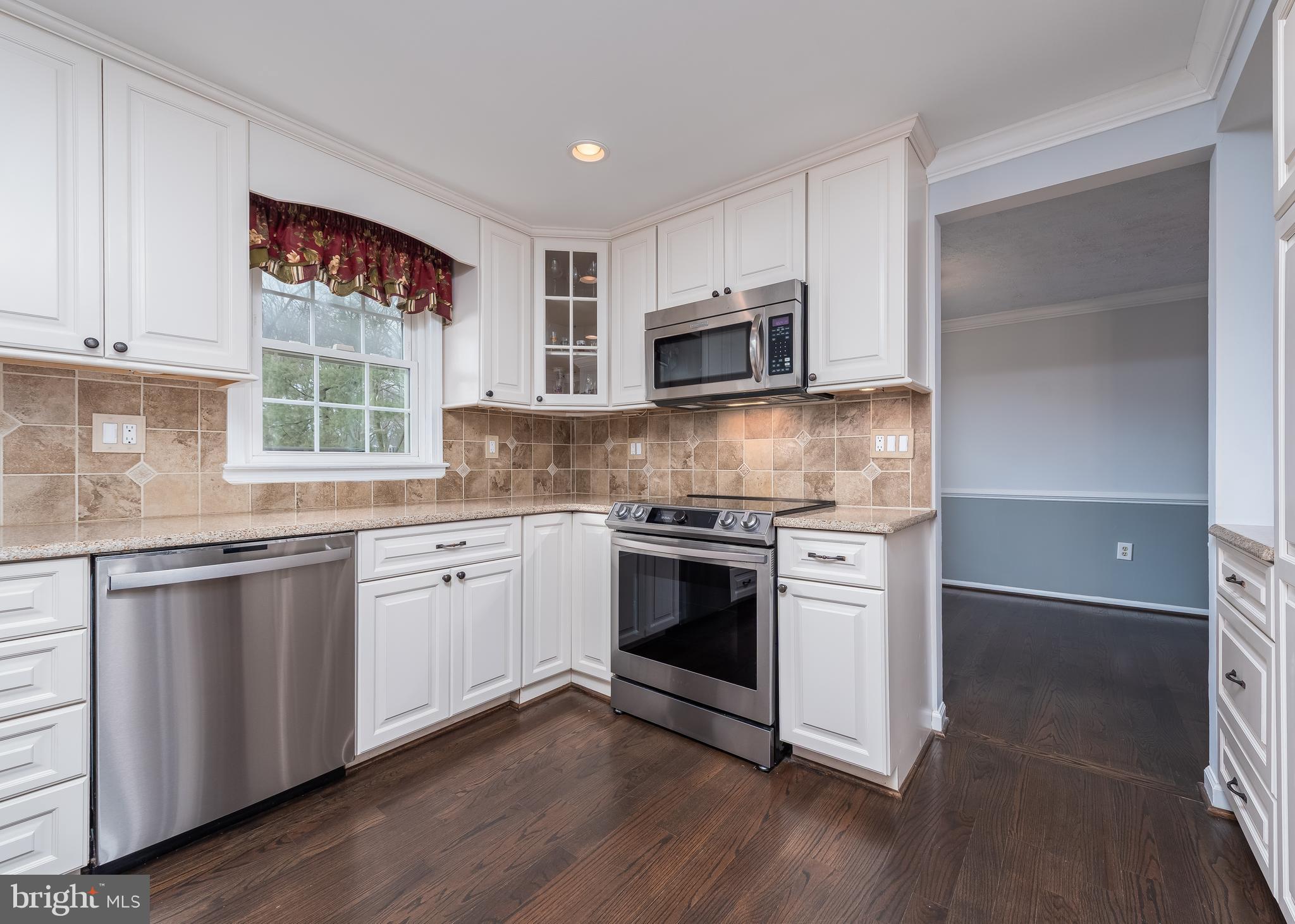 7202 Single Wheel Path Columbia, MD 21046 - Photo 8 of 30 a kitchen with granite countertop white cabinets a sink and wooden floor