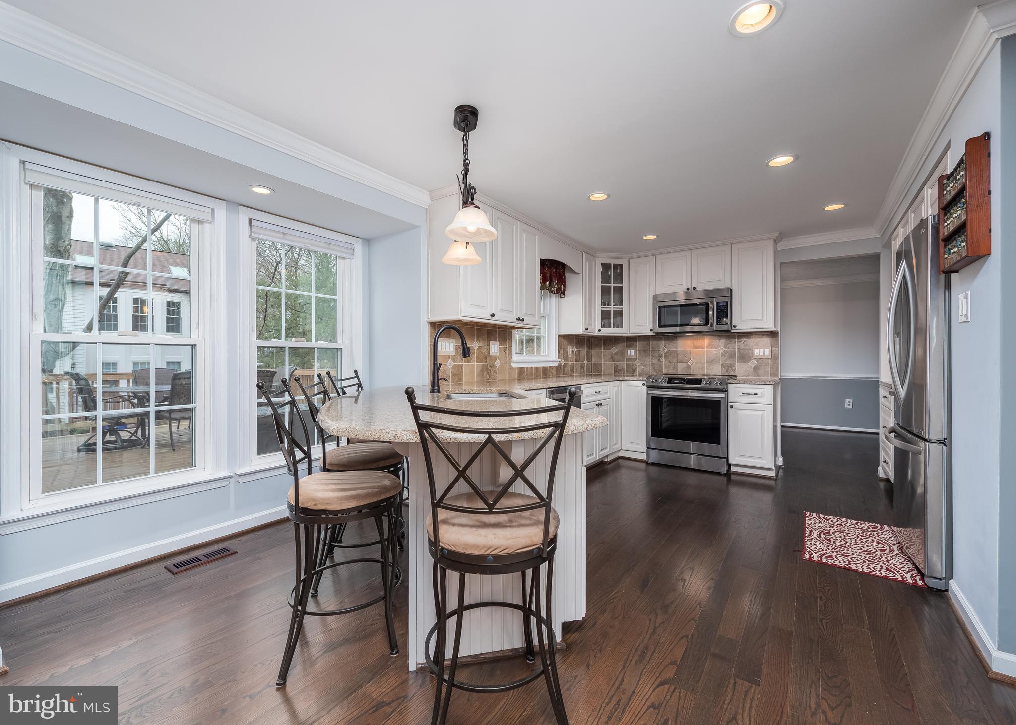 7202 Single Wheel Path Columbia, MD 21046 - Photo 9 of 30 a kitchen with stainless steel appliances granite countertop a table chairs refrigerator sink and cabinets