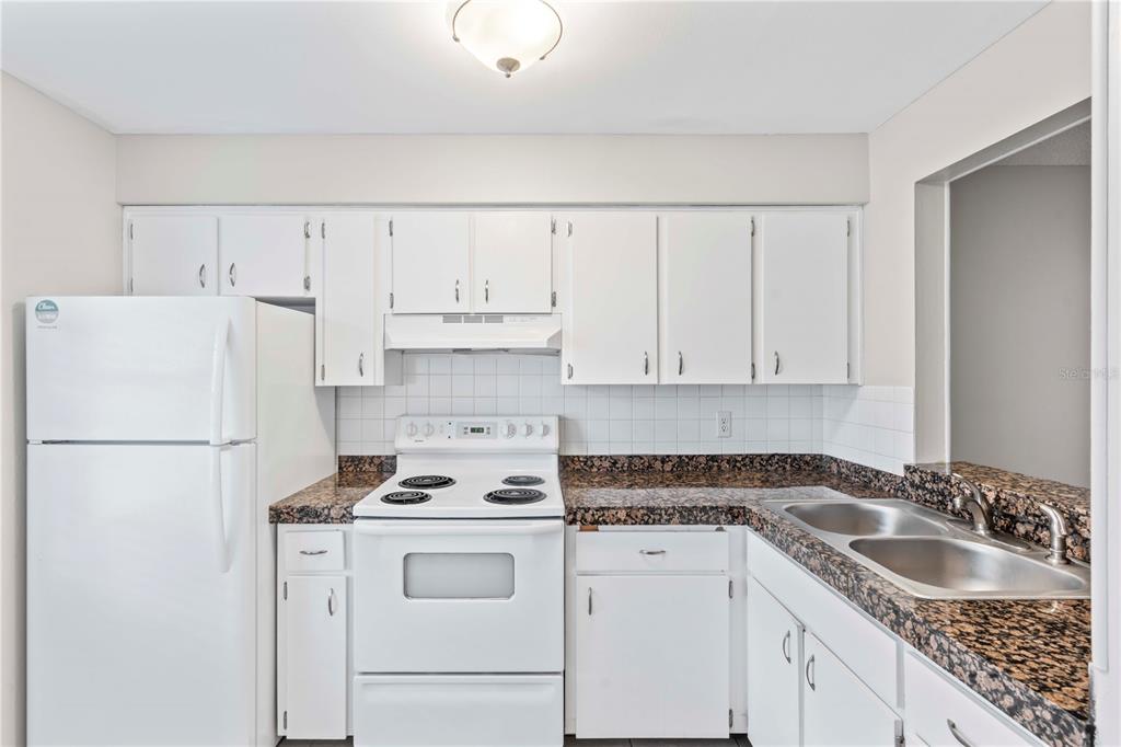 11511 113th Street, Unit 4F Largo, FL 33778 - Photo 4 of 30 a kitchen with granite countertop white cabinets and white appliances