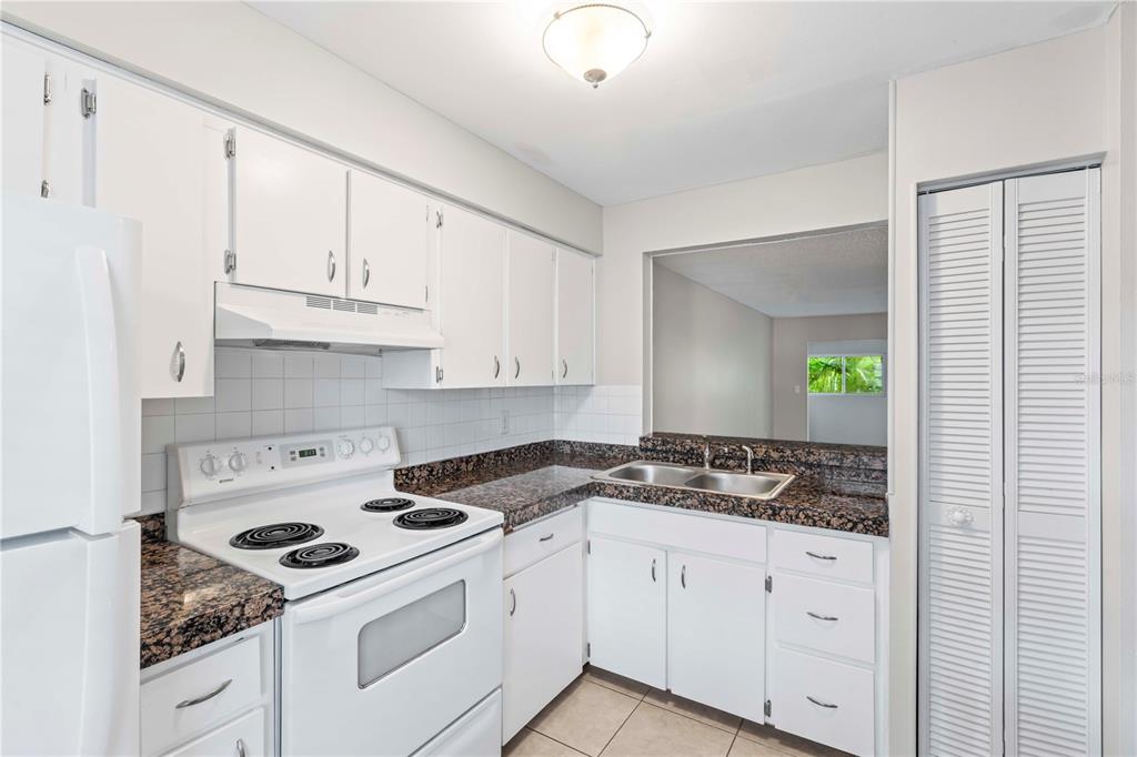 11511 113th Street, Unit 4F Largo, FL 33778 - Photo 7 of 30 a kitchen with granite countertop white cabinets and white appliances
