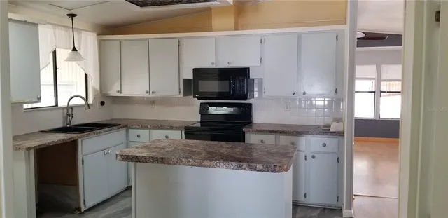 a kitchen with granite countertop a sink stove and refrigerator