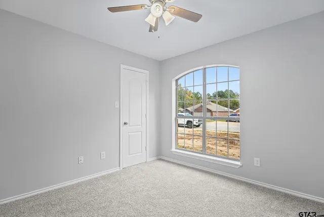 an empty room with windows and chandelier fan