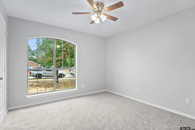 an empty room with a window and a ceiling fan