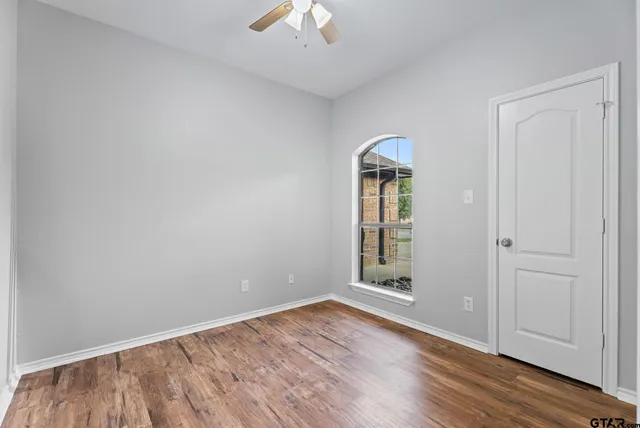 an empty room with wooden floor cabinet and windows