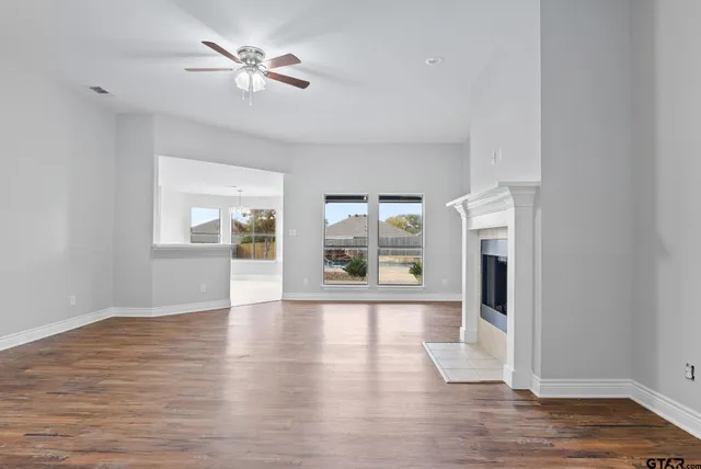 a view of an empty room with a window and wooden floor