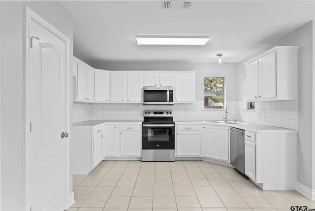 a kitchen with white cabinets and appliances