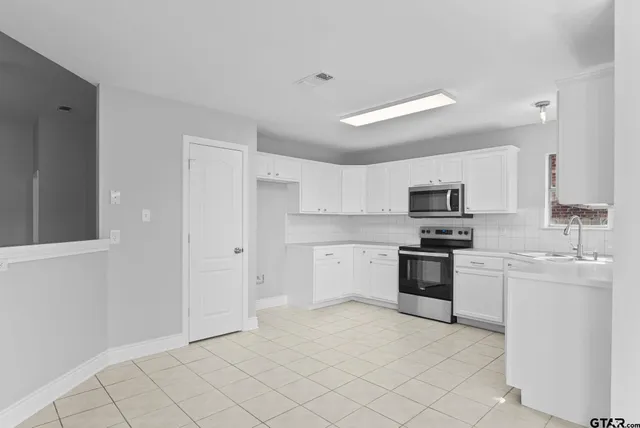 a kitchen with stainless steel appliances white cabinets a sink and a stove