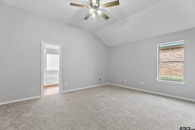 an empty room with chandelier fan and windows