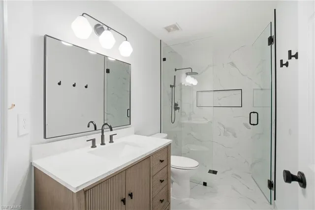 an empty room with wooden floor chandelier fan and windows