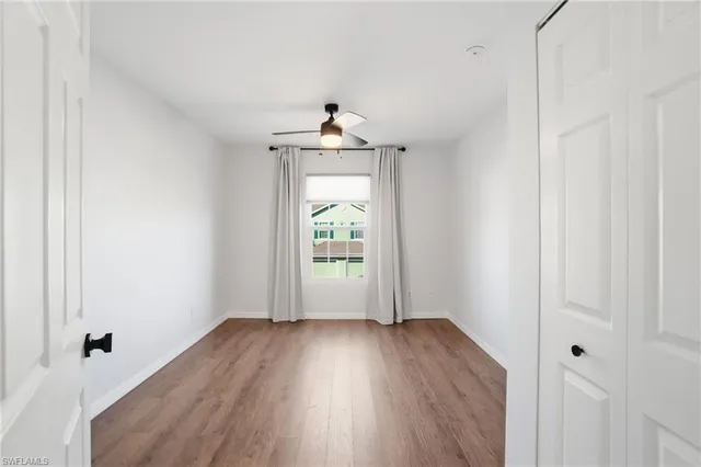 an empty room with wooden floor ceiling fan and windows