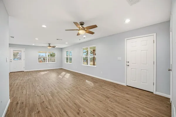 a view of an empty room with a window and wooden floor
