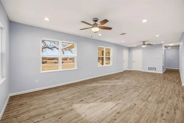 a view of empty room with wooden floor and fan
