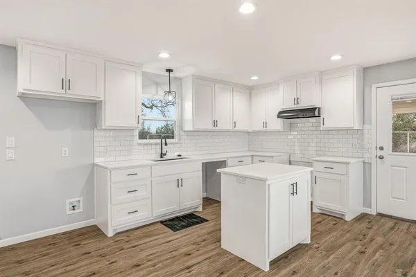a kitchen with cabinets stainless steel appliances a sink and wooden floor
