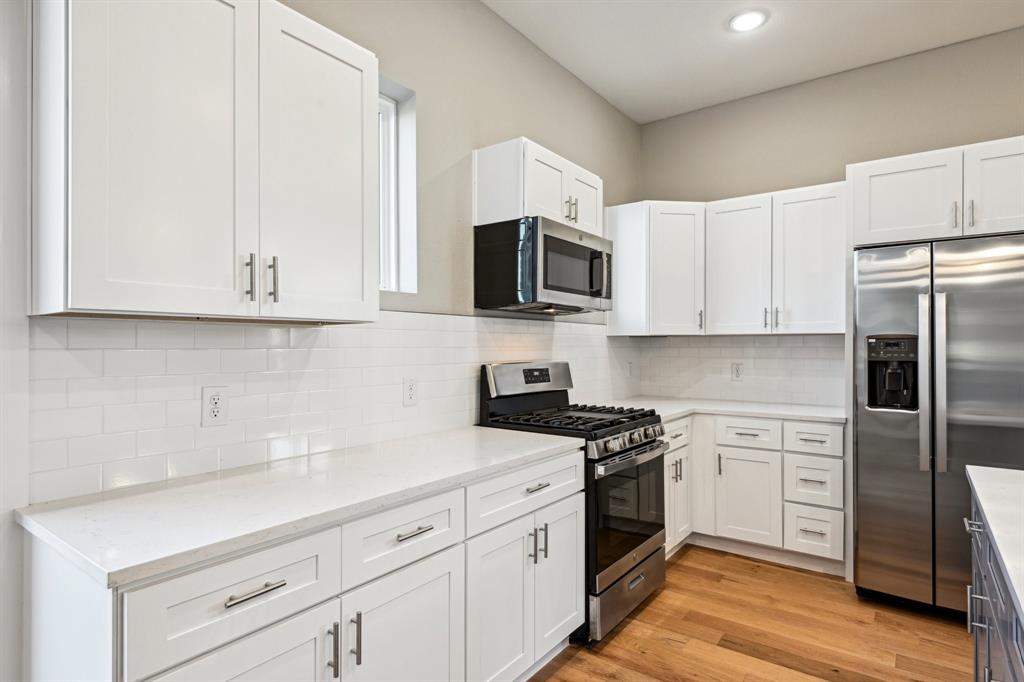 1711 Paytyn Drive Allen, TX 75013 - Photo 13 of 37 Kitchen with appliances with stainless steel finishes, tasteful backsplash, light stone counters, light hardwood / wood-style floors, and white cabinets