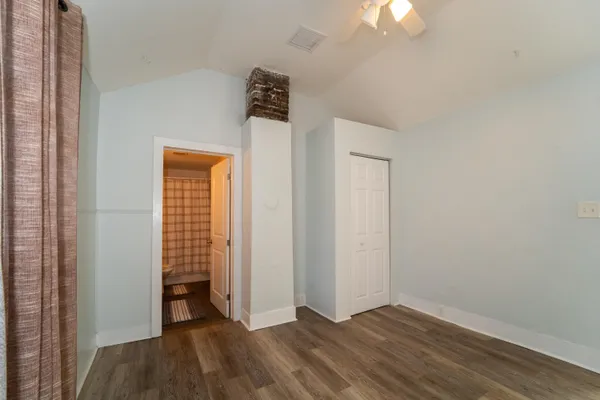 an empty room with wooden floor closet and windows