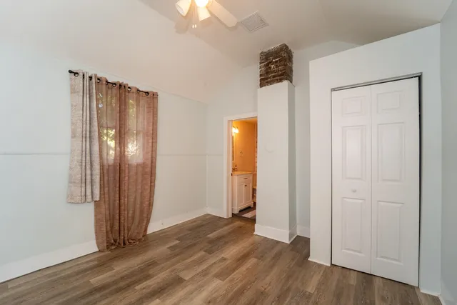 an empty room with wooden floor mirror and windows