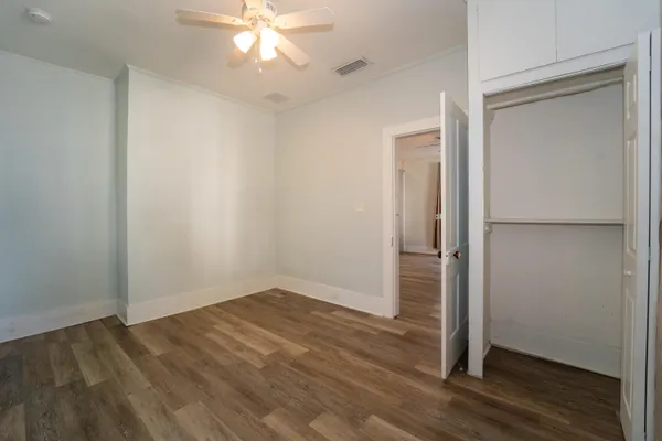 an empty room with wooden floor and closet area