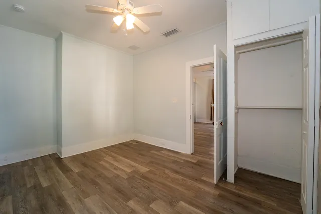 an empty room with wooden floor and closet area