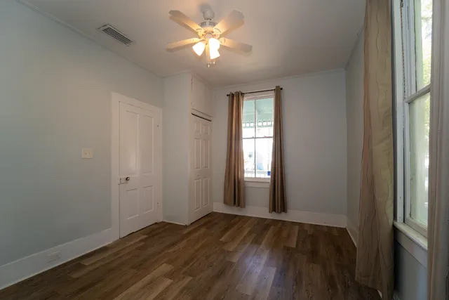 a view of empty room with wooden floor and fan