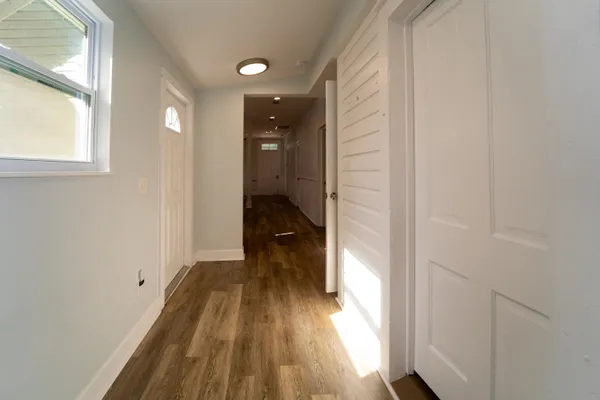 a view of a hallway with wooden floor and a bathroom