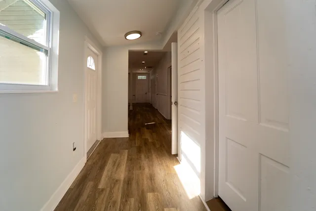 a view of a hallway with wooden floor and a bathroom