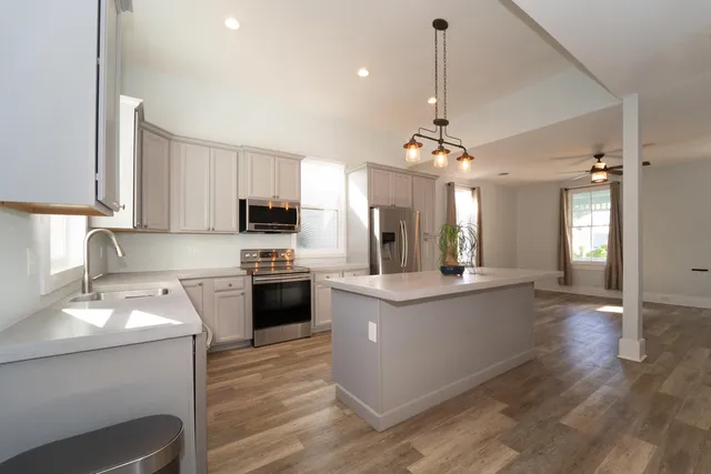a kitchen with a center island wooden floor and stainless steel appliances