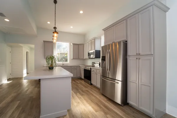a kitchen with kitchen island a counter top space a refrigerator and a view of living room