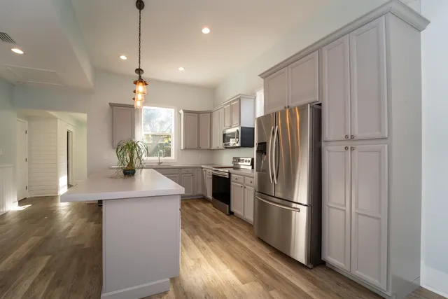 a kitchen with kitchen island a counter top space a refrigerator and a view of living room