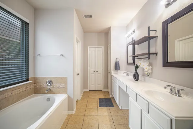 a spacious bathroom with a tub sink and mirror