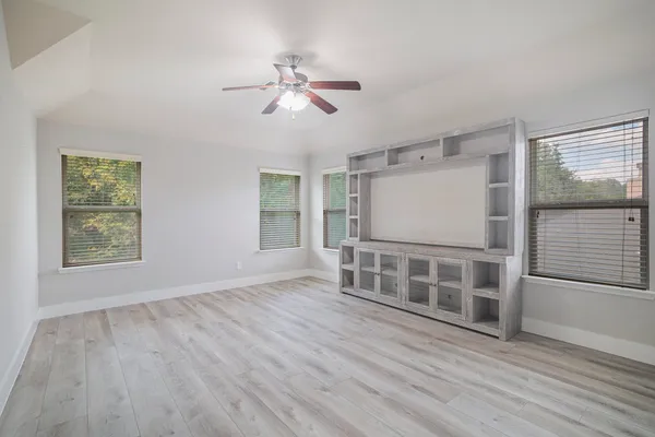 an empty room with a chandelier fan and windows