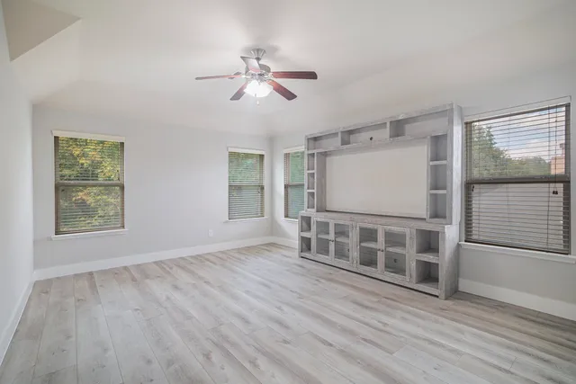 an empty room with a chandelier fan and windows