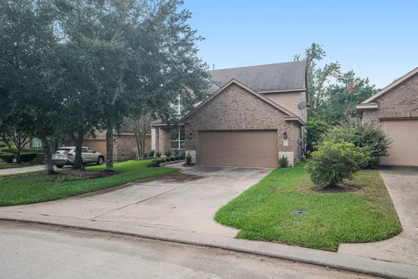 front view of house with a yard and trees all around